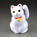 White cat figurine with a yellow bell on a gray background.