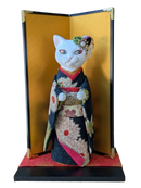 Cat-shaped doll in traditional Japanese kimono with a gold stand.