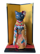 Maneki neko in traditional Japanese kimono with a gold screen.