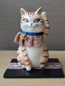 Cat-shaped figurine with a decorative collar on a wooden surface.